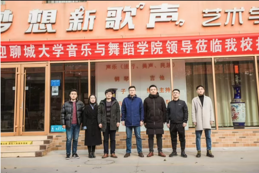 学校教师与到校交流人员在校门前合影